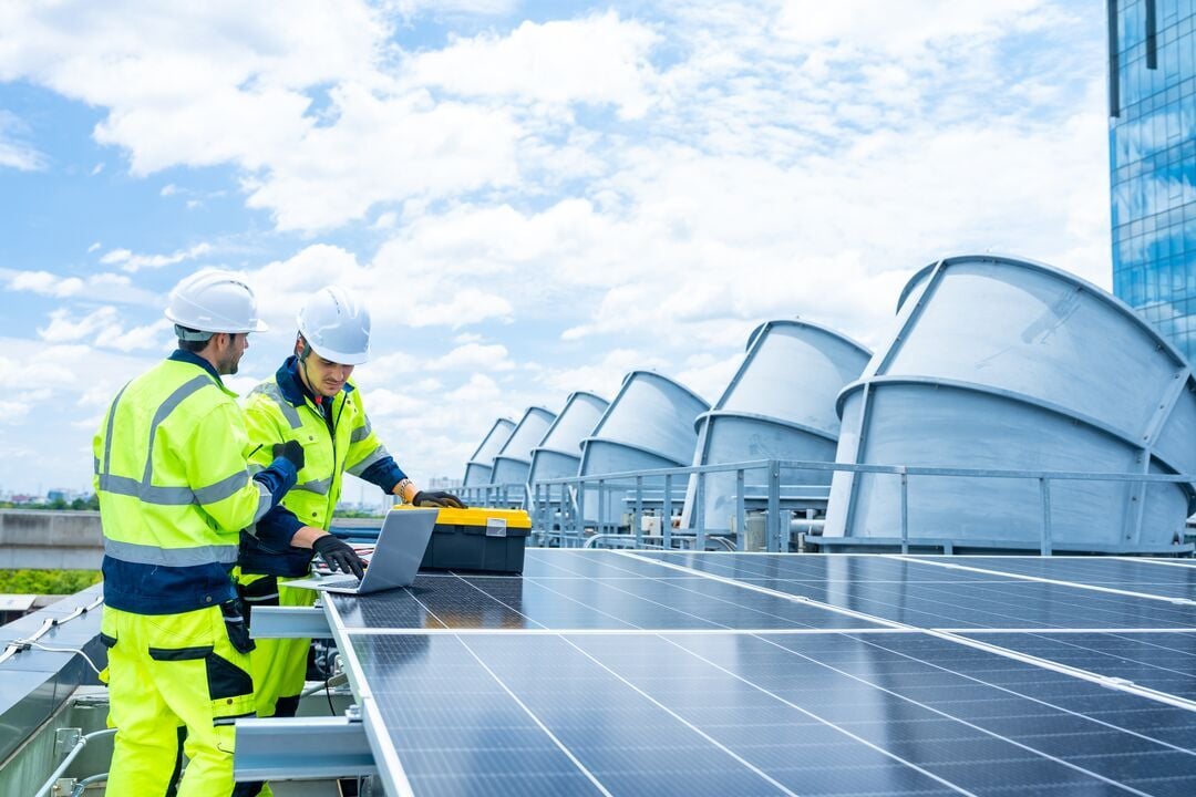 Kaksi huoltohenkilöä asentamassa aurinkopaneelia.