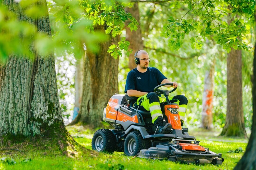 ISS:n kiinteistöhoitaja ajamassa nurmikkoa.